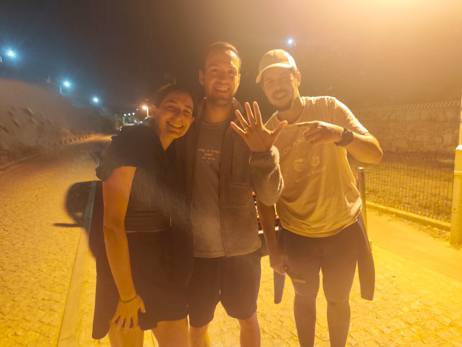 A couple and our detectorist on the promenade at Vale Centeanes at night, the man holding up his hand with the wedding ring back on his finger