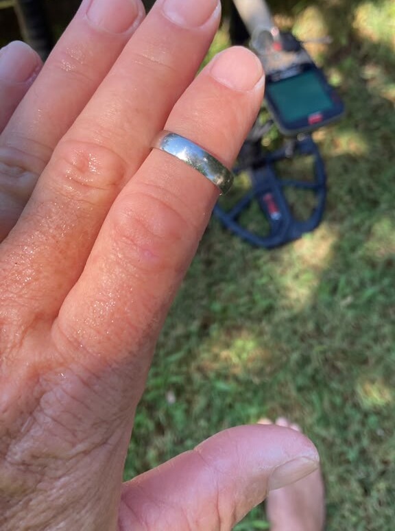 Richard's platinum wedding ring back on his hand after it was found in the sea in Vlorë, with the metal detector lying on the grass behind