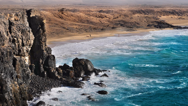 Golden sandstone cliffs above a sandy Algarve beach and turquoise Atlantic water, the kind of beach near Albufeira or Lagos where a lost ring can be buried by the tide