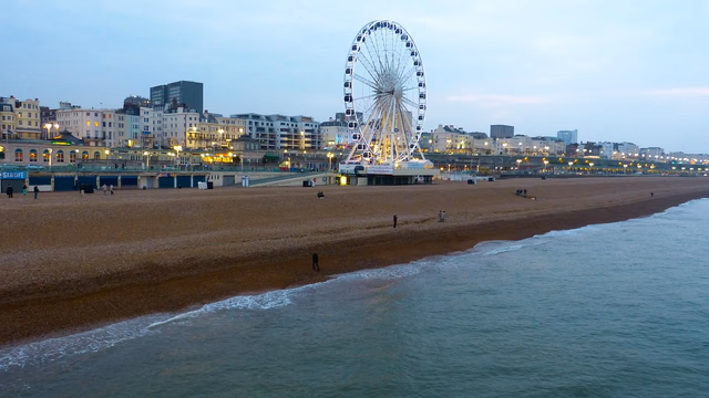The pebble beach at Brighton with the pier reaching out over a calm blue sea, the kind of shingle shore where a lost ring can slip down between the stones
