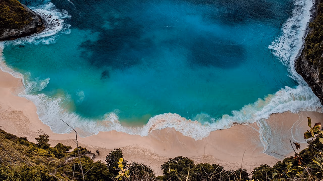Turquoise water and a small sandy beach below rocky cliffs on the west coast of Curaçao, the kind of calm cove where a lost ring stays close to where it fell