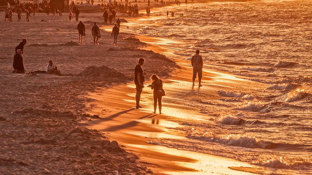 A long stretch of golden sand on the Adriatic coast near Venice, rows of beach umbrellas and calm shallow water, the kind of beach at Lido di Jesolo where a lost ring stays close to where it fell