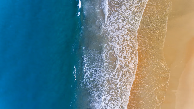 Waves rolling onto the golden sand of Bondi Beach in Sydney under a blue sky, the kind of surf beach where a lost ring or wedding band is quickly covered by moving sand